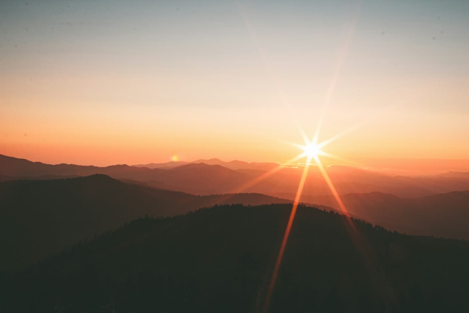 Sunlight falling over layers of forested mountains